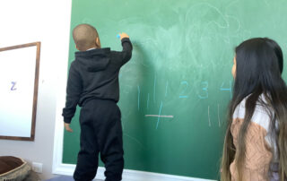 Eyas Landing child writing on chalkboard during evaluation